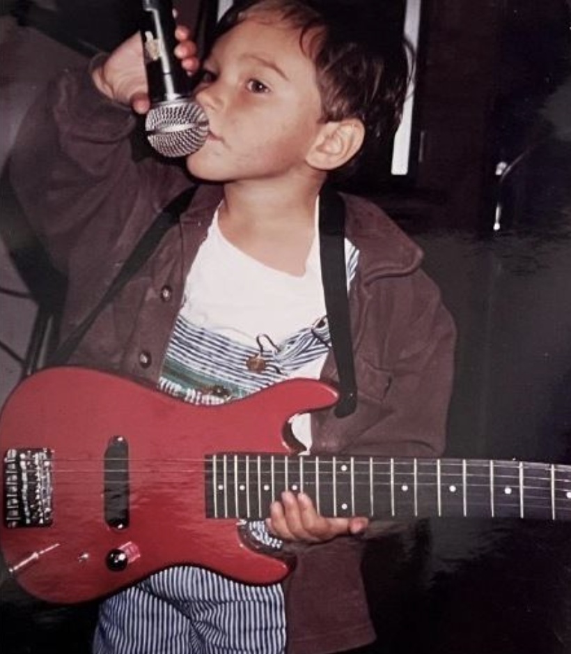 Lucas Long as a toddler holding a guitar and microphone